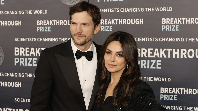 Ashton Kutcher and Mila Kunis posing on step-and-repeat