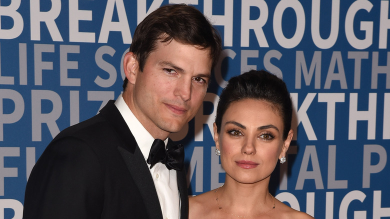Ashton Kutcher and Mila Kunis posing on step-and-repeat