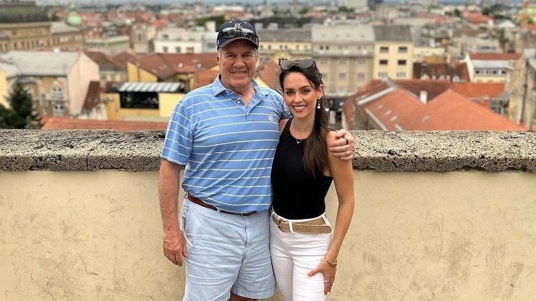 Bill Belichick and Jordon Hudson posing outdoors on a roof
