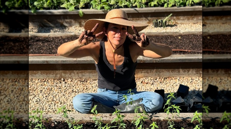 Joanna Gaines sitting outside in a garden and wearing a sunhat