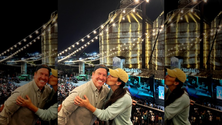 Joanna Gaines kissing Chip Gaines in front of silos of their Magnolia retail space in Waco
