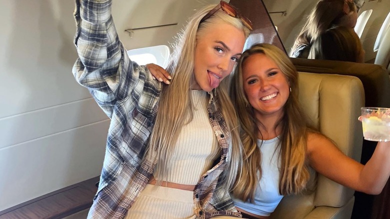 Alex Cooper lifting a glass with a friend on a jet in 2021