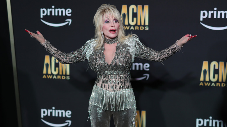 Dolly Parton raising her arms on the red carpet of the ACM Awards