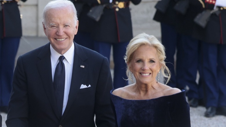 Joe and Jill Biden smiling outside surrounded by guards