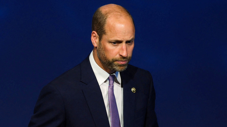 Prince William frowning and looking down in front of him