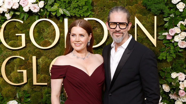 Amy Adams smiling in a maroon gown beside Darren Le Gallo at the Golden Globes