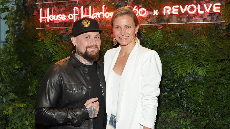 Cameron Diaz smiling and wearing white beside Benji Madden smiling and wearing black