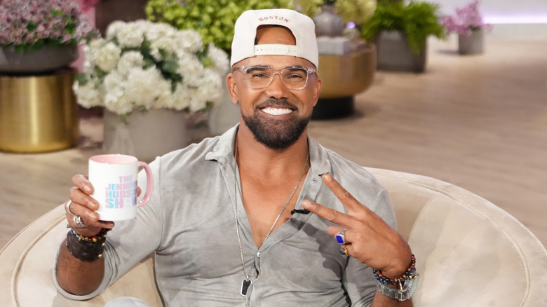 Shemar Moore holding a mug and giving a peace sign