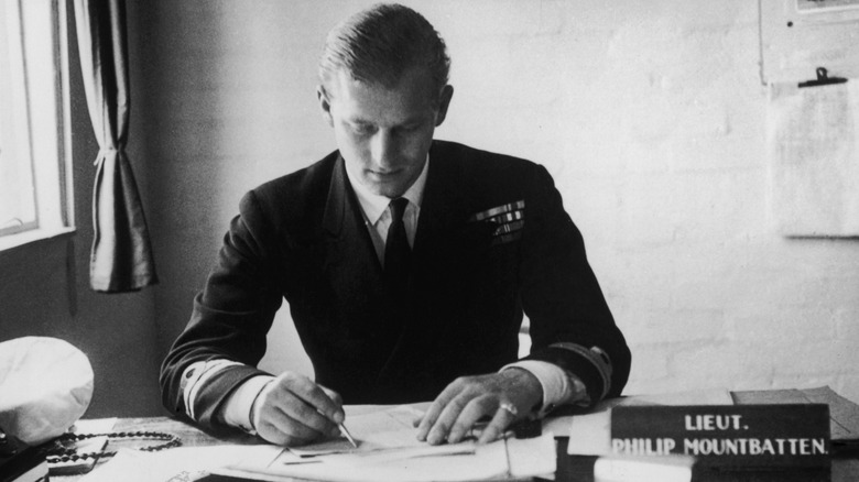 A young Prince Philip writing at his desk