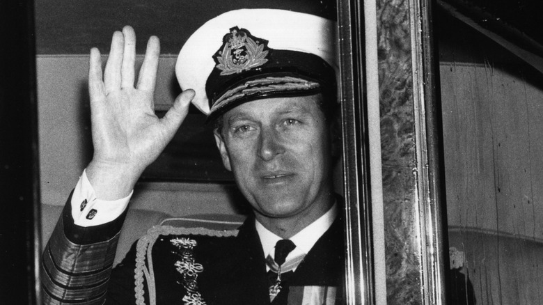 A middle-aged Prince Philip waving from a carriage window