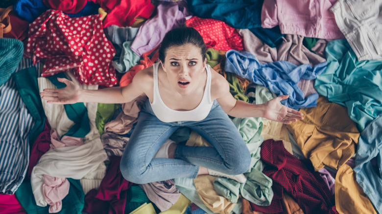 Stressed-looking woman surrounded by clothing