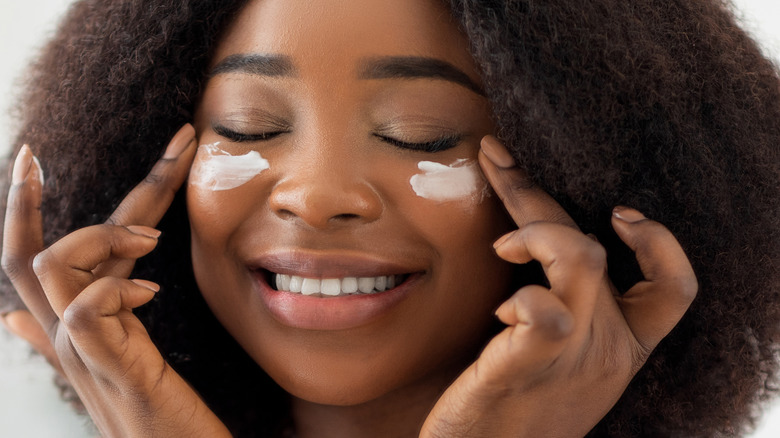 Woman smiling applying eye cream