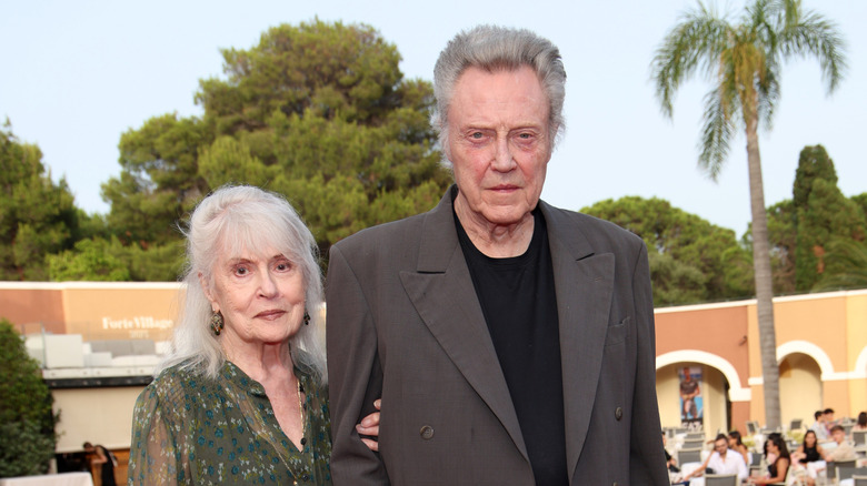 Georgianne Walken in a green outfit holding Christopher Walken's arm.
