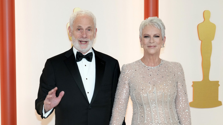 Jamie Lee Curtis in a sequinned silver dress beside Christopher Guest at the Oscars.