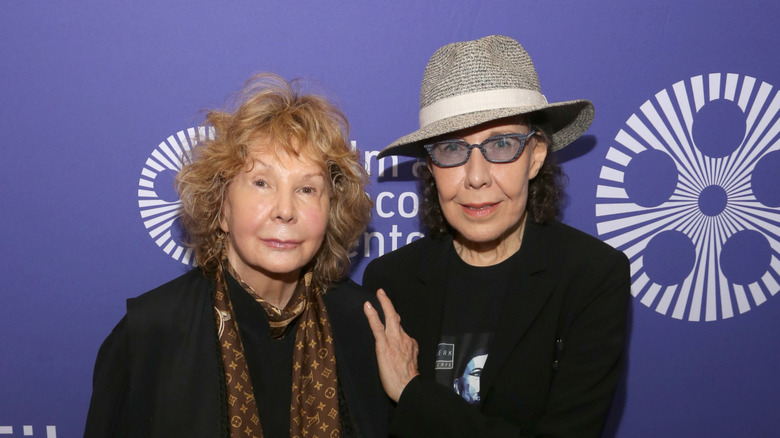 Lily Tomlin in a hat and tinted glasses beside Jane Wagner.