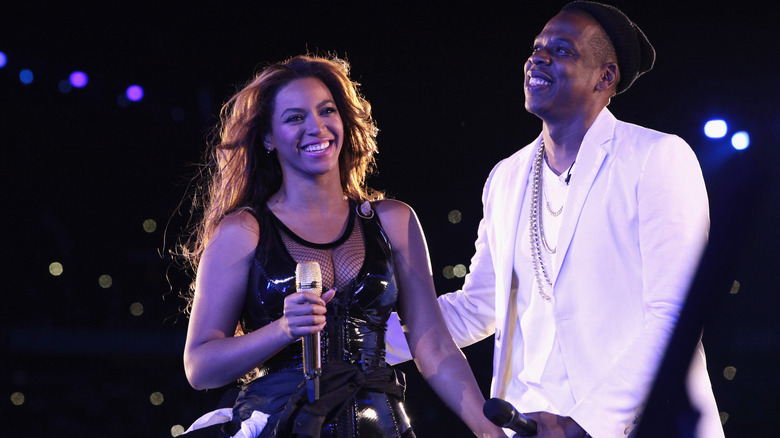 Beyonce in black laughing beside Jay-Z in white