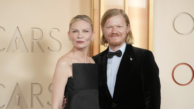 Kirsten Dunst laughing in pink dress as Jesse Plemons looks on