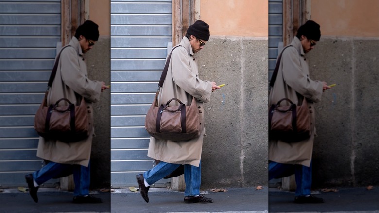 Harry Styles walking down the street looking at his phone