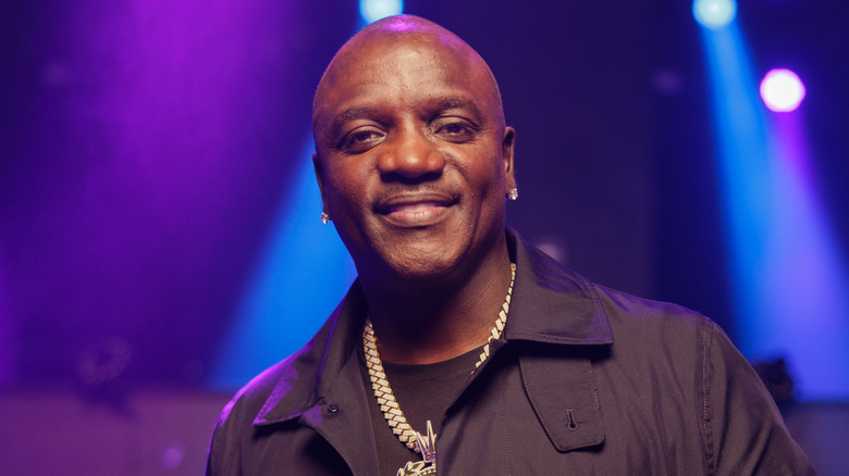 Akon posing for a photo with purple and blue lights in the background