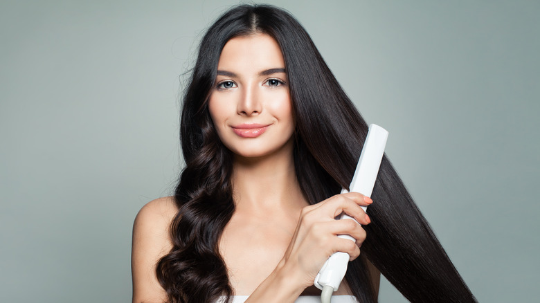 Woman straightening her curly hair