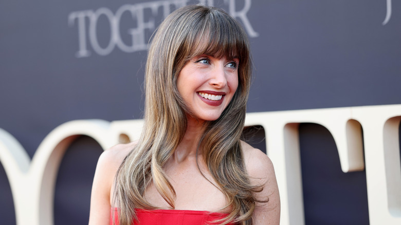 Alison Brie in a red strapless outfit and long fringed hair