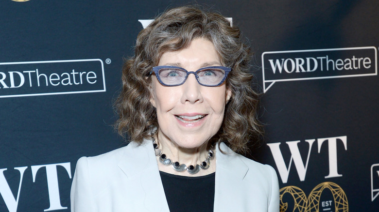 Closeup of Lily Tomlin smiling on step-and-repeat wearing glasses