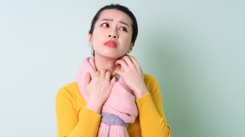 Woman in a scarf scratching her neck 