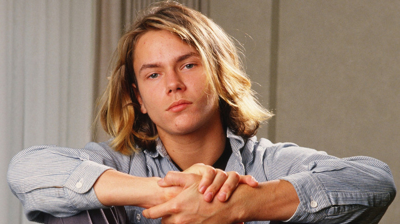River Phoenix sitting with hands clasped