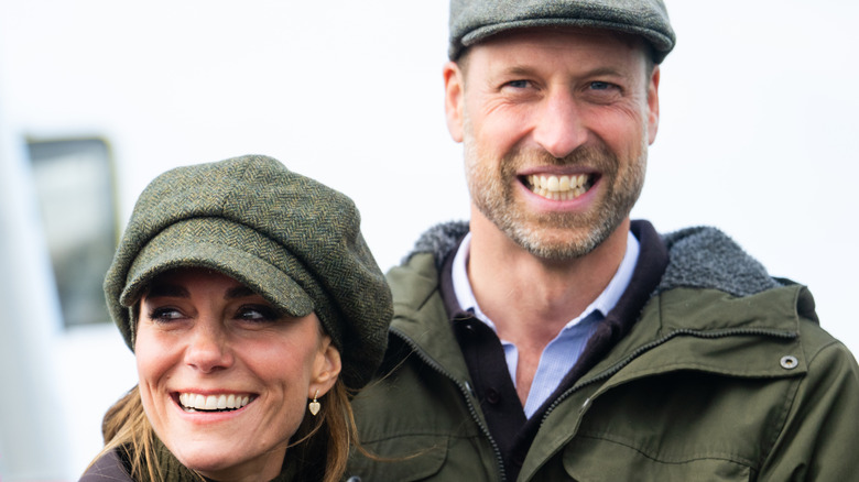 Kate Middleton and Prince William smiling and wearing similar hats