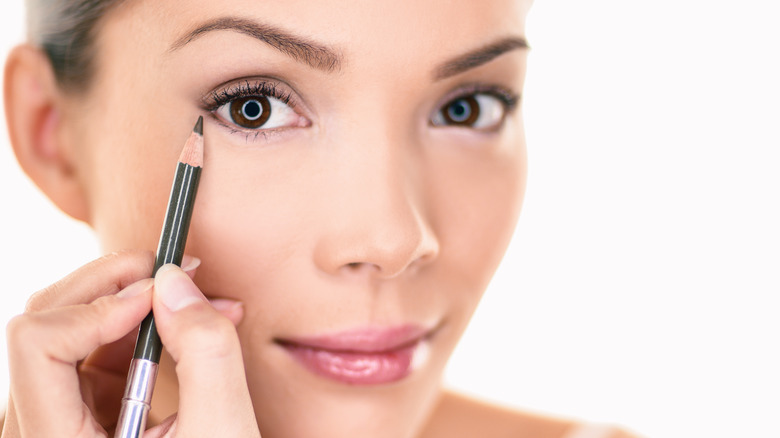 Woman putting on eyeliner