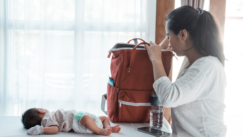 woman looking through diaper bag next to baby