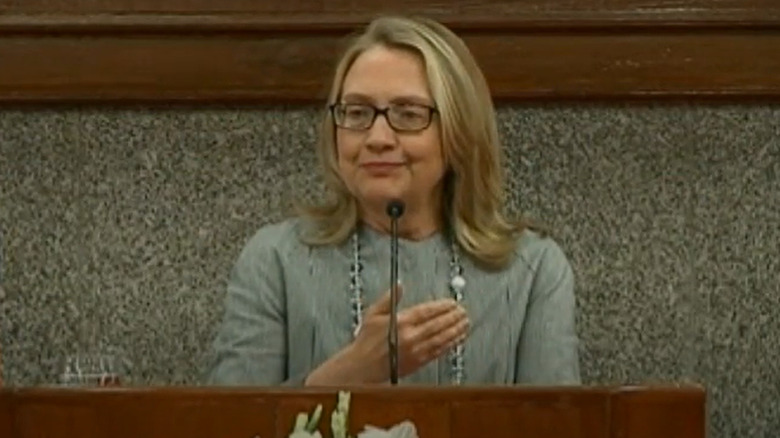 Hillary Clinton speaking at a podium while wearing glasses