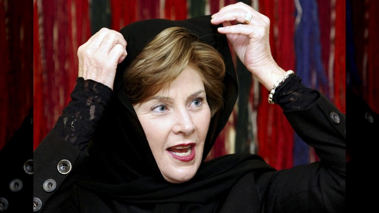 Laura Bush placing a black hijab on her head