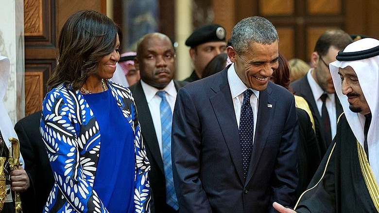 Michelle and Barack Obama smiling while chatting with a Saudi official