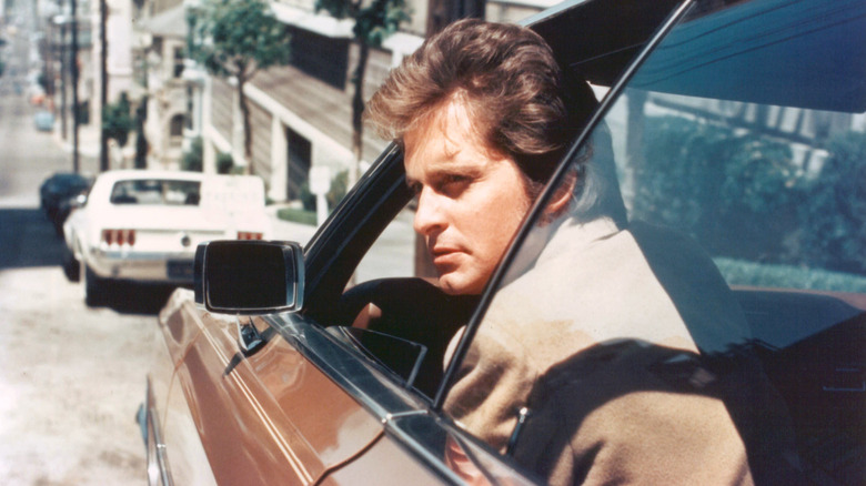 Michael Douglas looking out of car while filming 
