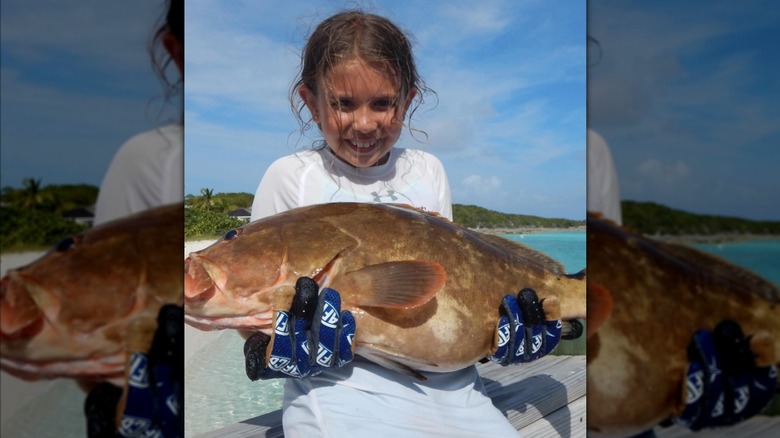image of a young Kai Trump holding up a heavy fish
