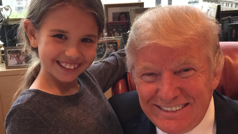 image of a young Kai Trump smiling and standing next to Donald Trump