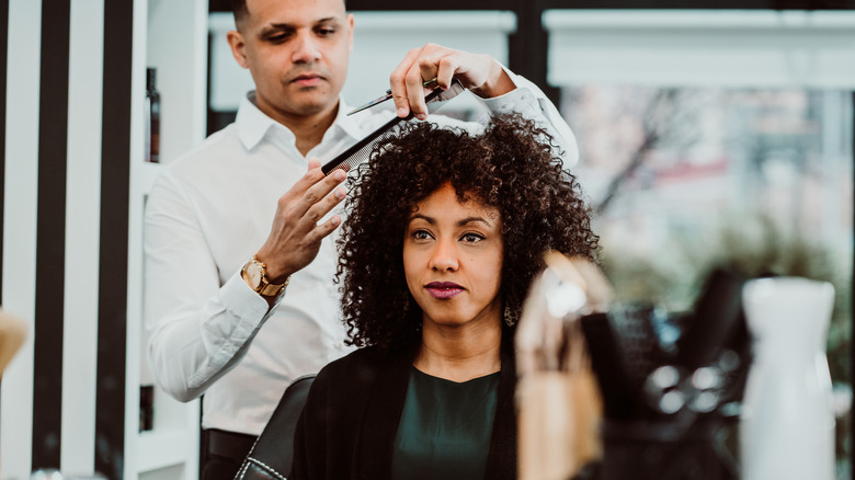 person with curly brown hair getting hair done at a hair salon