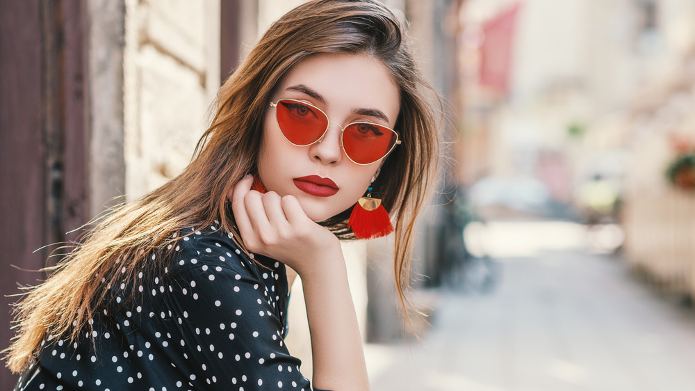 A woman wearing red sunglasses and earrings