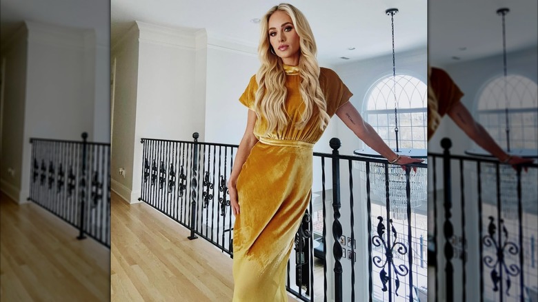 Tomi Lahren wearing a gold velvet dress and leaning against a railing