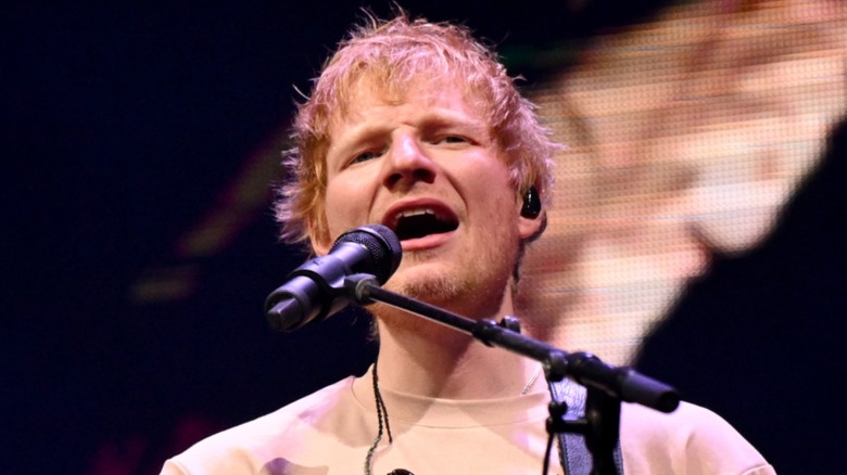 A close up of Ed Sheeran singing on-stage in 2025.