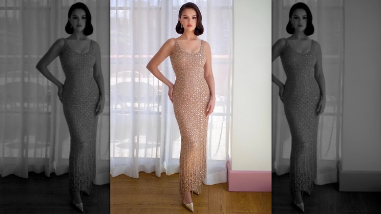 Selena Gomez in a champagne-colored dress, standing in front of sheer curtains.