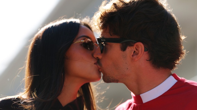 A close up of Alexandra and Charles Leclerc kissing in the sunlight.