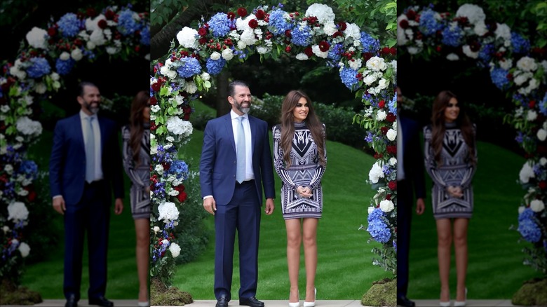 Kimberly Guilfoyle and Donald Trump Jr. standing under decorative floral archway