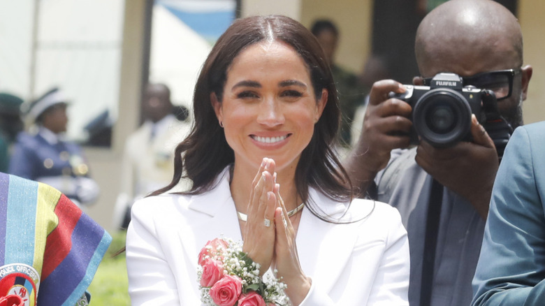 Meghan Markle smiling surrounded by crowds and photographers
