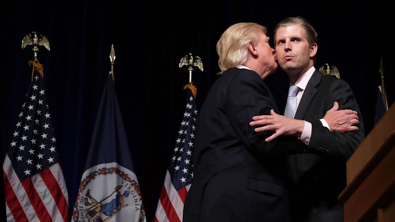 Donald Trump kissing his son Eric Trump on the cheeks as they grab each other's arms at a 2016 campaign event in Virginia.