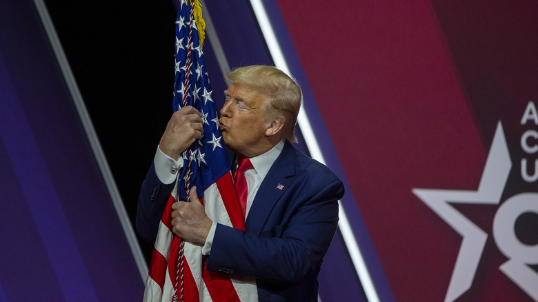 Donald Trump grabbing an American flag with both hands and kissing it at CPAC 2020.