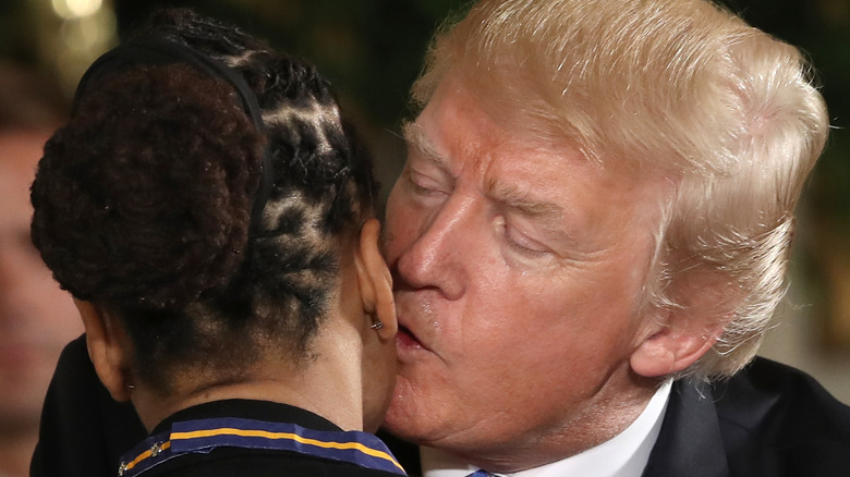 Donald Trump kissing the ear of officer Crystal Griner while presenting her with a medal.