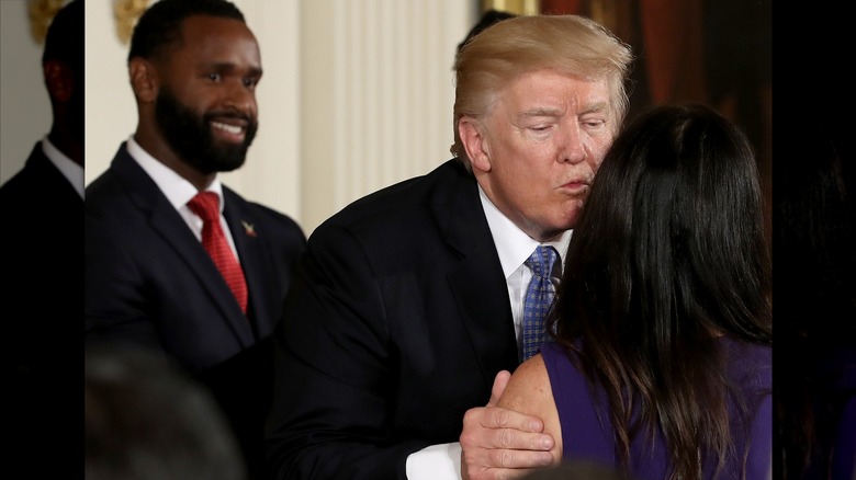Donald Trump's face looking sweaty as he leans down to kiss Jennifer Scalise, whose back is to the camera.