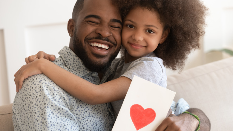 Man holding a heart-themed card and young girl